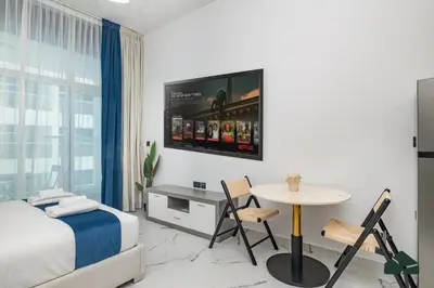 a bedroom with a bed and a table and a tv at Peaceful Studio in Opalz by Danube by BMS in Dubai