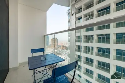 a blue table and chairs in a room with a window at Peaceful Studio in Opalz by Danube by BMS in Dubai