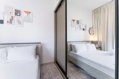 two beds in a bedroom with a mirror at HAVN - Spacious One Bedroom in Binghatti Creek in Dubai