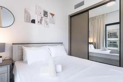 a bedroom with a large white bed and a mirror at HAVN - Spacious One Bedroom in Binghatti Creek in Dubai
