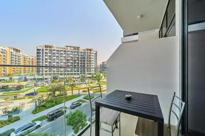 a balcony with a table and a view of a city at Bright & Cozy Studio in Vibrant Azizi Riviera in Dubai