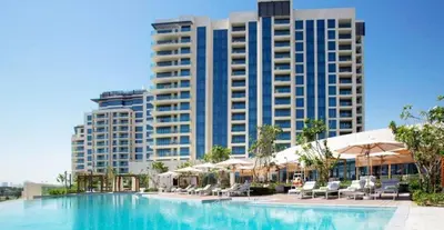 a pool with chairs and umbrellas in front of a building at HAVN - 2 Bed Burj Khalifa View, Access Dubai Mall in Dubai