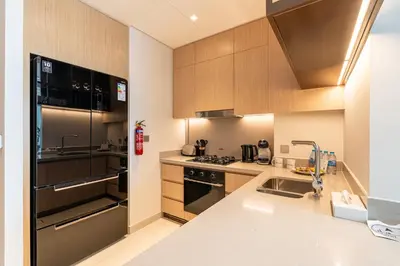 a kitchen with stainless steel appliances and wooden cabinets at HAVN - 2 Bed Burj Khalifa View, Access Dubai Mall in Dubai