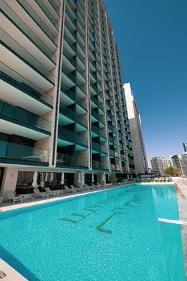 a large swimming pool next to a tall building at Binghatti Trillionaire! 2 Double Beds! Private Jacuzzi, Prime Location! in Dubai