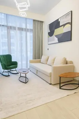 a living room with a couch and a green chair at Azizi in Dubai