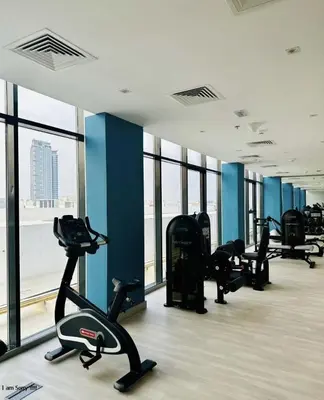 a gym with treadmills and ellipticals in a room with windows at Azizi in Dubai
