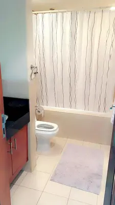 a bathroom with a toilet and a shower curtain at Cozy private master bedroom for solo female in shared home in Dubai