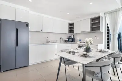 a white kitchen with a dining table and chairs at Burj Khalifa View From The Infinity Pool 2BR at Downtown Dubai in Dubai