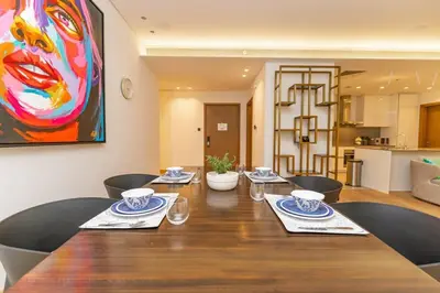 a dining room table with chairs and a painting on the wall at Chic 2Bedroom And Maids Room Apartment Mins from Dubai Mall in Dubai