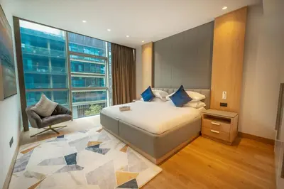 a bedroom with a bed and a chair and a window at Chic 2Bedroom And Maids Room Apartment Mins from Dubai Mall in Dubai