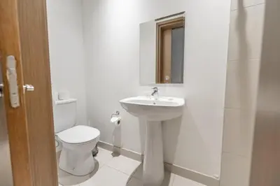 a white bathroom with a toilet and a sink at Spacious Two Bedroom with Maids room Near City Mall in Dubai