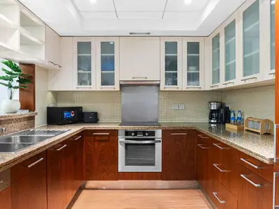 a kitchen with wooden cabinets and a stove top oven at Cozy 1BR Downtown Burj View in Dubai