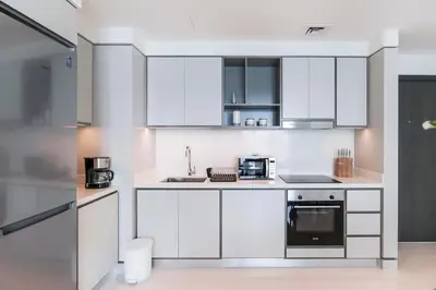a white kitchen with white cabinets and appliances at Elegant 1BR at Sunrise Bay with Stunning Palm View in Dubai