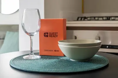 a glass of wine and a bowl and a book on a table at GuestReady - 1BR l Stylish City Escape in Dubai