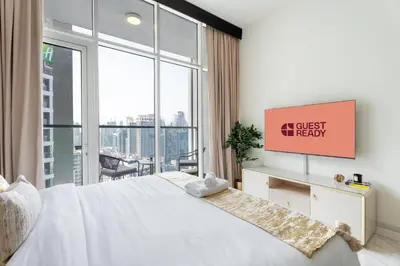 a bedroom with a white bed and a large window at GuestReady - Studio | Stunning Burj Khalifa View in Dubai