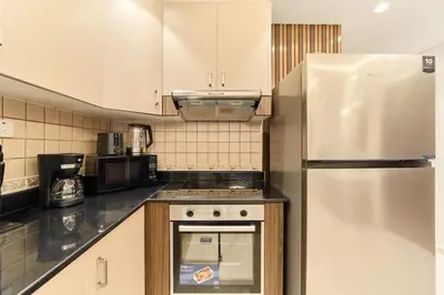a kitchen with white cabinets and a stainless steel refrigerator at Bright 1BR Apartment in Elite Residence Marina in Dubai