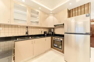 a kitchen with white cabinets and a stainless steel refrigerator at Bright 1BR Apartment in Elite Residence Marina in Dubai