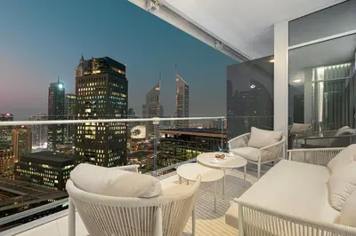 a balcony with white chairs and a view of a city at Burj Daman By Luxe Living - Future Museum & Emirates Towers Views in Dubai