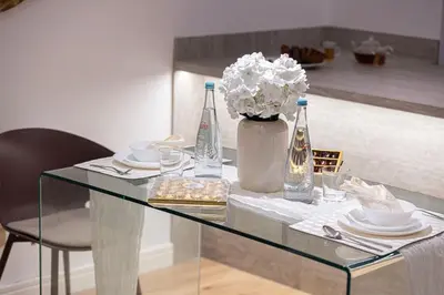 a glass table with a vase of flowers and bottles at Burj Daman By Luxe Living - Future Museum & Emirates Towers Views in Dubai