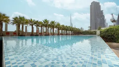 a large swimming pool with palm trees in a city at Burj Daman By Luxe Living - Future Museum & Emirates Towers Views in Dubai