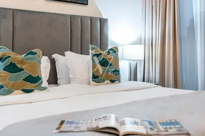 a book laying on a bed with pillows at La Vie Majestic 2BDR with Private Beach Access in Dubai