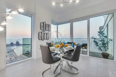 a dining room with a table and chairs and large windows at La Vie Majestic 2BDR with Private Beach Access in Dubai