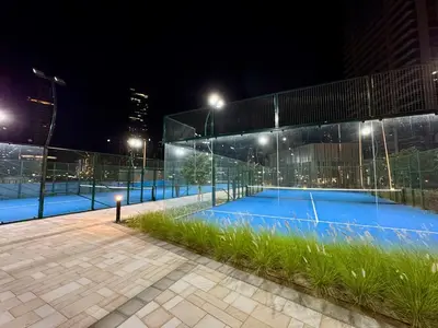 a tennis court at night with lights on it at Skyline Escape 2 bedroom with Burj Khalifa View in Dubai