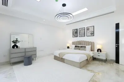 a white bedroom with a bed and a mirror at Exclusive Golf Villa 5BR with Pool and Game Room in Dubai