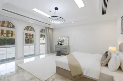 a white bedroom with a bed and a desk at Exclusive Golf Villa 5BR with Pool and Game Room in Dubai
