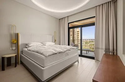 a white bedroom with a bed and a balcony at Brand New Luxury 2BHK Apartment in Jadeel 2 MJL in Dubai
