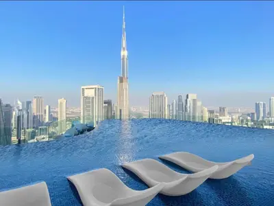 two white chairs sitting on top of a pool with a city skyline at Morden 2BR With Full sea view -High floor in Dubai