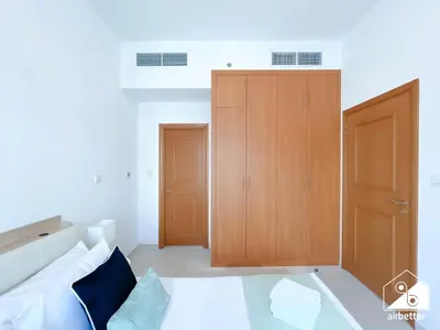 a bedroom with a bed and two wooden cabinets at 1BR City Escape at Marina Residence Pool & Gym in Dubai