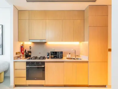 a kitchen with wooden cabinets and a stove and a sink at Vida Dubai Mall - Luxury 1BR with Direct access to Dubai Mall in Dubai