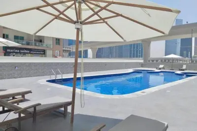 a pool with an umbrella and two chairs and a table at Locations l Elegant 1 Bedroom l Skyline Views l Dubai Marina in Dubai