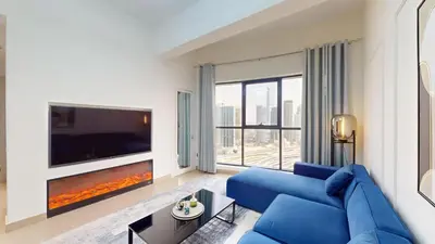 a living room with a blue couch and a large tv at Locations l Elegant 1 Bedroom l Skyline Views l Dubai Marina in Dubai