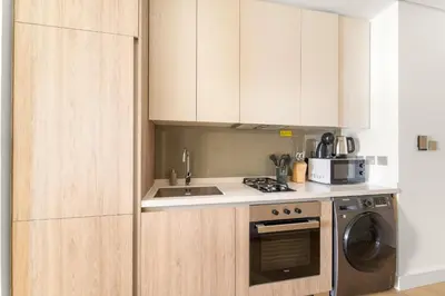 a kitchen with white cabinets and a sink and a dishwasher at VayK - Bright Studio Overlooking The Canal in Business Bay in Dubai
