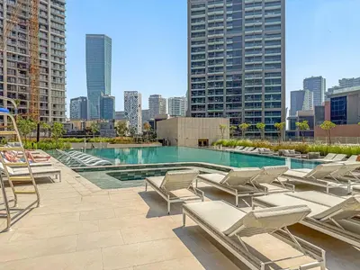 a pool with lounge chairs and a city skyline at VayK - Bright Studio Overlooking The Canal in Business Bay in Dubai
