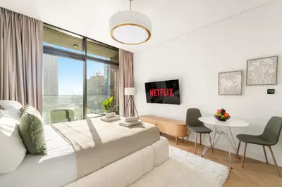a white bedroom with a bed and a table and chairs at VayK - Bright Studio Overlooking The Canal in Business Bay in Dubai