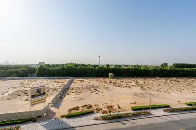 a large empty parking lot with trees in the background at Relaxing Studio with Balcony & Pool in Haven Tower in Dubai