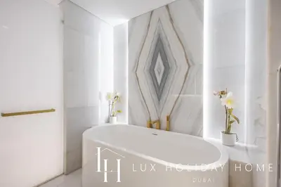 a white tub in a bathroom with flowers on the wall at LUX The Five Palm Jumeirah Suite in Dubai