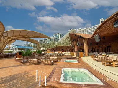 a resort patio with a hot tub and tables and chairs at LUX The Five Palm Jumeirah Suite in Dubai