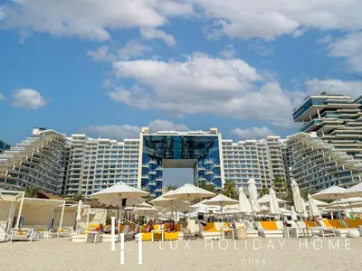 a beach with umbrellas and chairs and buildings at LUX The Five Palm Jumeirah Suite in Dubai