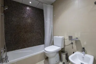 a bathroom with a toilet and a tub and a sink at Stylish 2BR Oasis in Business Bay with Pool & Gym in Dubai