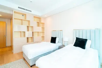a bedroom with two beds and a book shelf at 2BR With Rooftop Pool Offering Burj Khalifa Views in Dubai