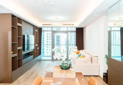 a living room with a white couch and a tv at 2BR With Rooftop Pool Offering Burj Khalifa Views in Dubai