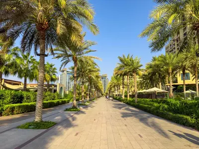 a sidewalk lined with palm trees in front of a building at Palm Jumeirah Sea-View Stay - Infinity Pool - Beach - Gym - Padel in Dubai