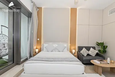 a bedroom with a large white bed and a chair at MarvelStay - Beach 5 mins - Fits 3 - Pool-Gym-Sauna - Marina in Dubai