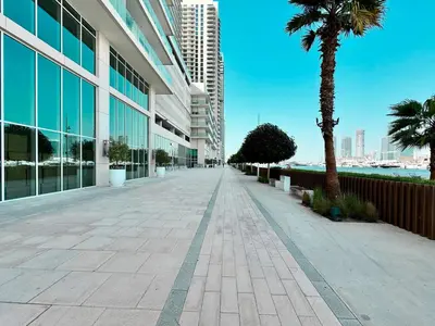 a sidewalk in front of a building with a palm tree at Direct Beach Access 2BHK in Dubai