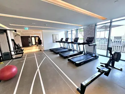 a gym with a row of treadmills and a woman at Direct Beach Access 2BHK in Dubai