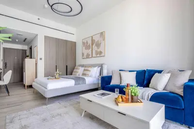 a living room with a blue couch and a bed at Frank Porter - Grove by Eman in Dubai